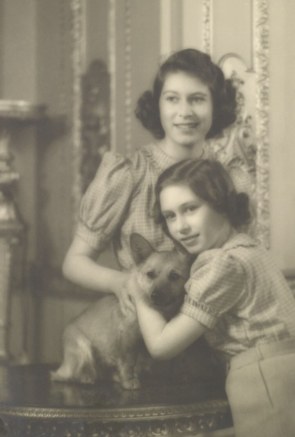 Queen Elizabeth II and Princess Margaret hold Dookie, the first of her corgis.